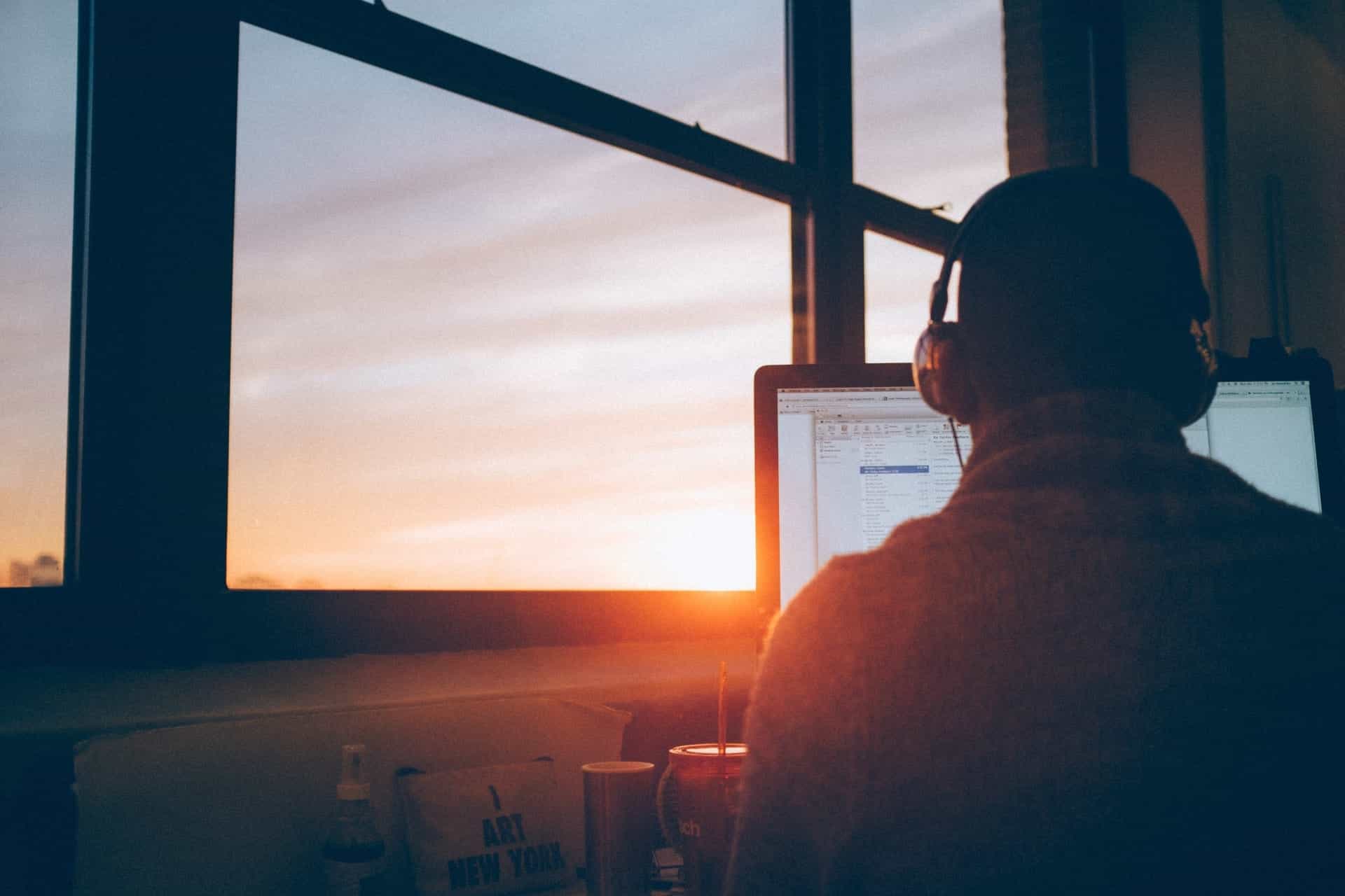 Man remote working with sunset streaming in through window