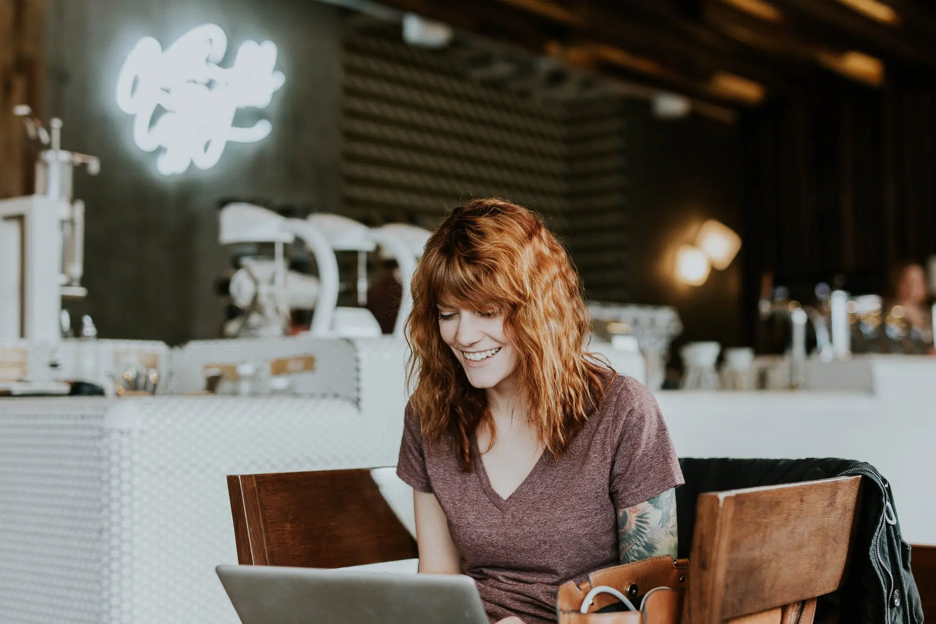 Woman with orange hair working on her laptop in a trendy cafe