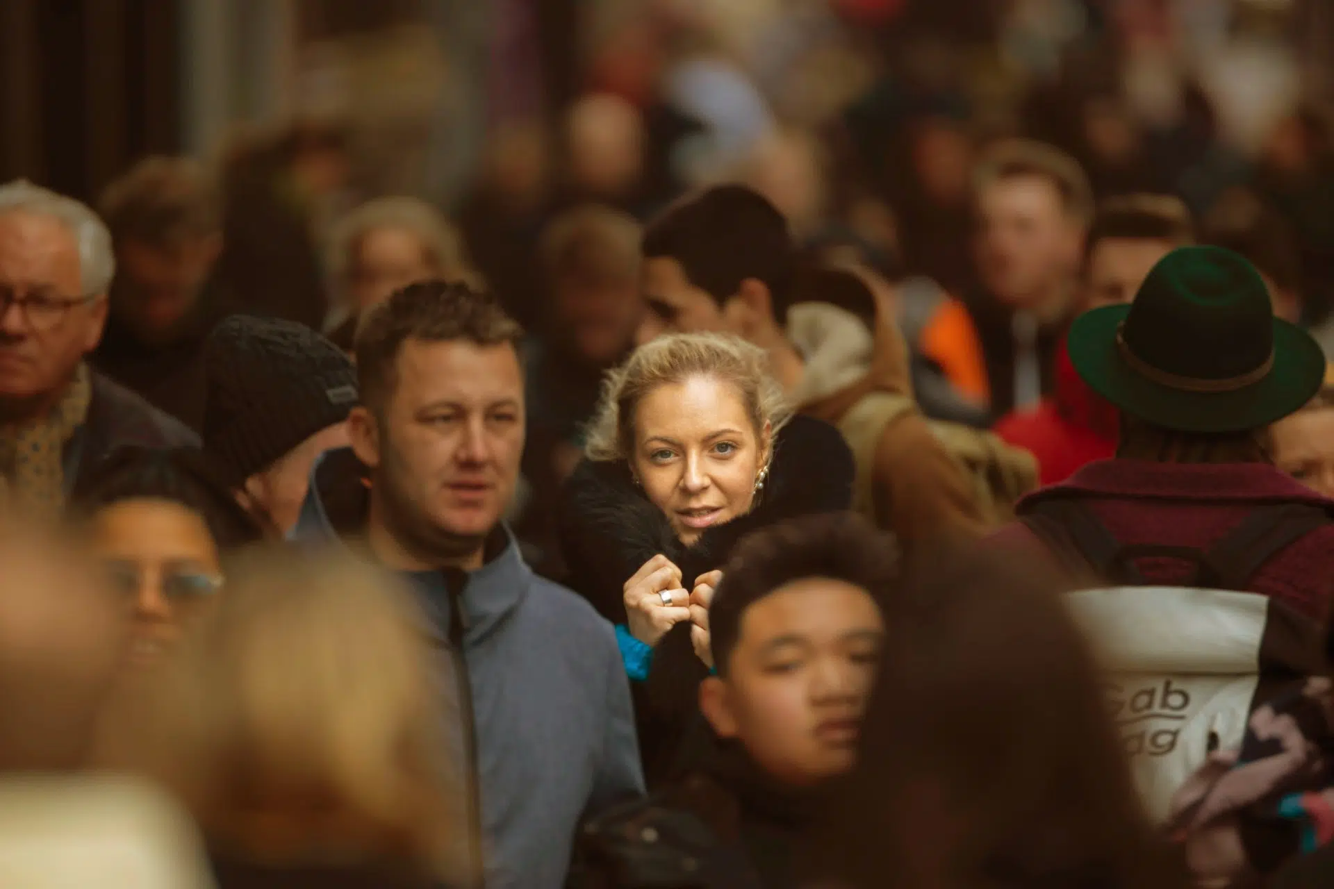 Photo of a crowd walking at rush hour with a woman standing out looking at the camera