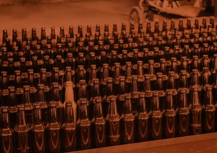 Rows of dark beer bottles with a single light bottle standing out