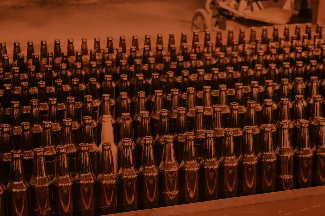 Rows of dark beer bottles with a single light bottle standing out