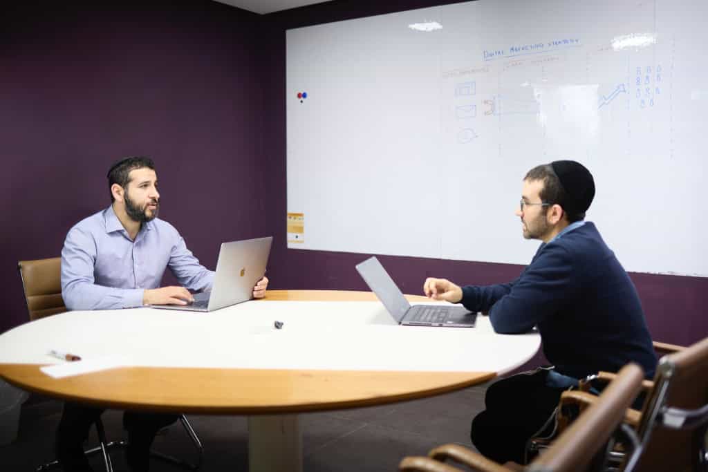 Raph and Joel discussing marketing strategy in an office meeting room