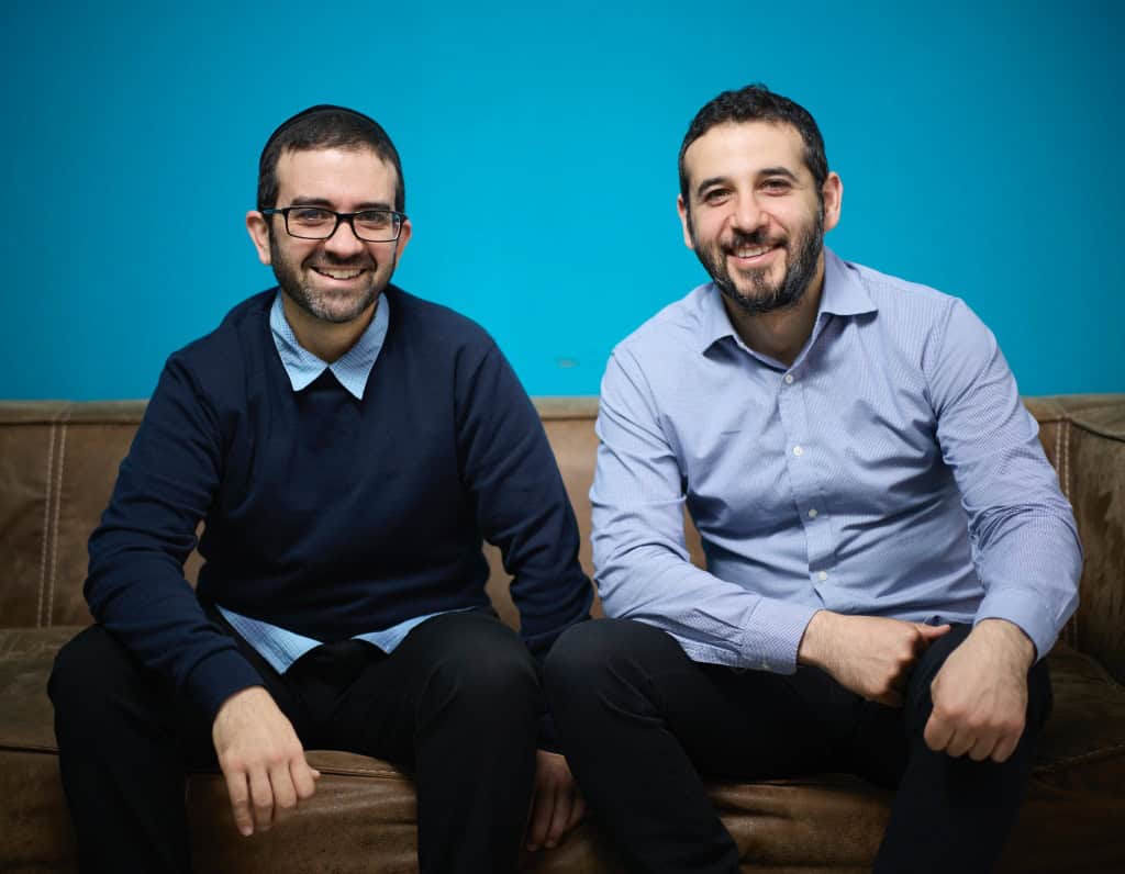 Joel and Raph of Digital Autopilot sitting on a brown sofa looking into the camera