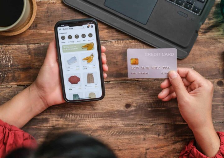 Woman buying clothing on her mobile phone with credit card out