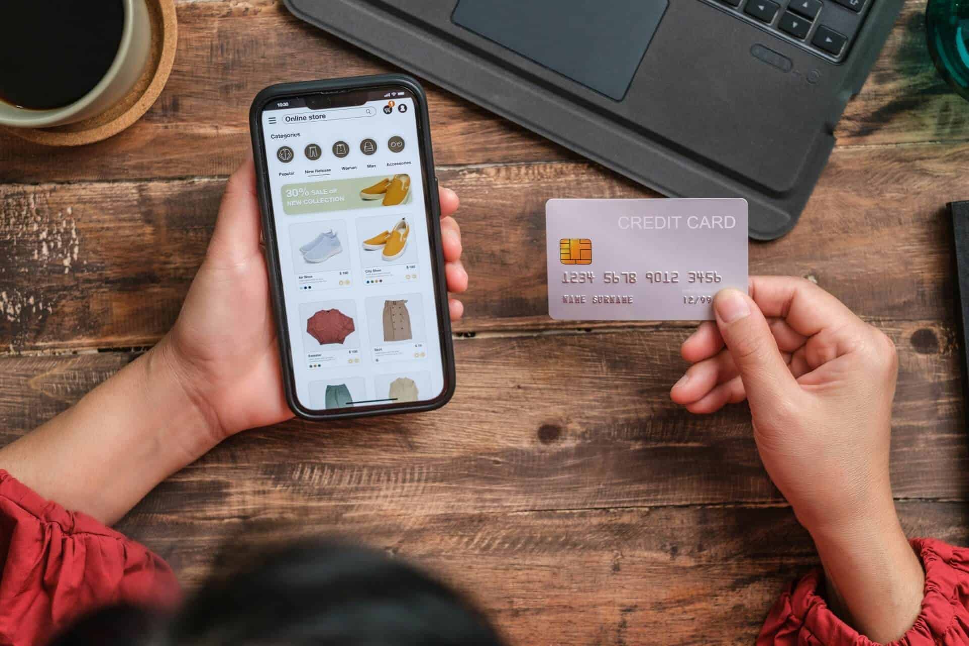 Woman buying clothing on her mobile phone with credit card out